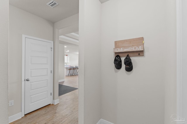 corridor featuring visible vents, baseboards, and light wood-style floors