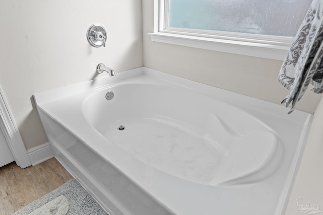 bathroom with a garden tub and wood finished floors