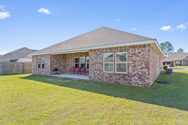 back of property featuring brick siding, a patio area, a yard, and fence