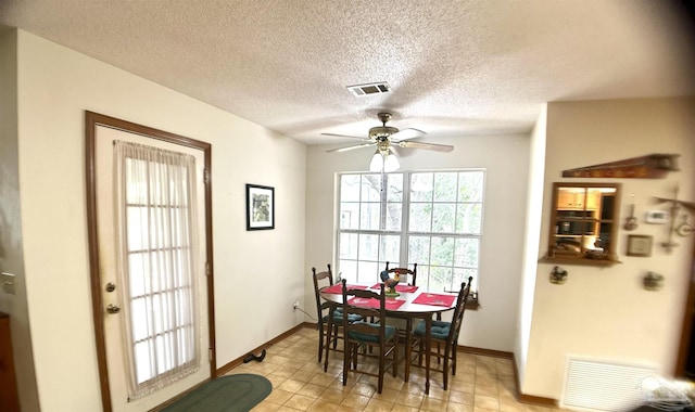 dining area featuring ceiling fan and a textured ceiling