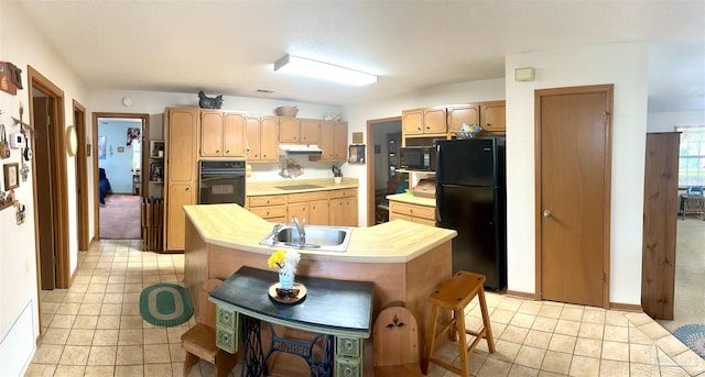 kitchen with a center island, black appliances, a kitchen breakfast bar, sink, and light tile patterned floors