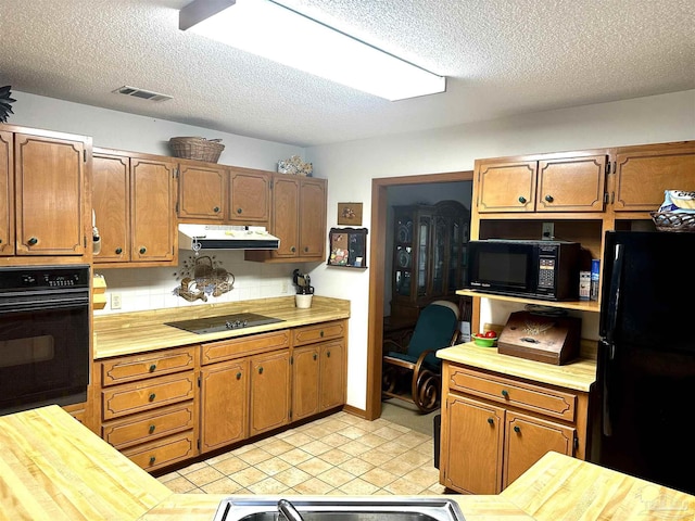 kitchen featuring tasteful backsplash, black appliances, and a textured ceiling