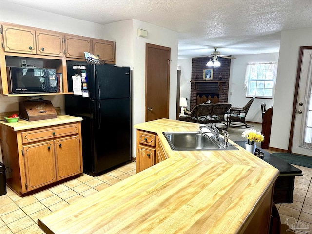 kitchen with a fireplace, sink, light tile patterned flooring, and black appliances