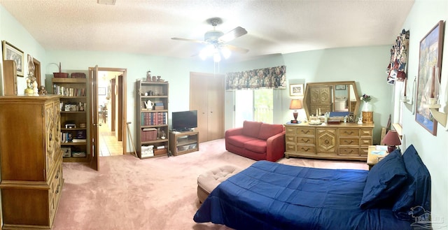 carpeted bedroom with ceiling fan and a textured ceiling