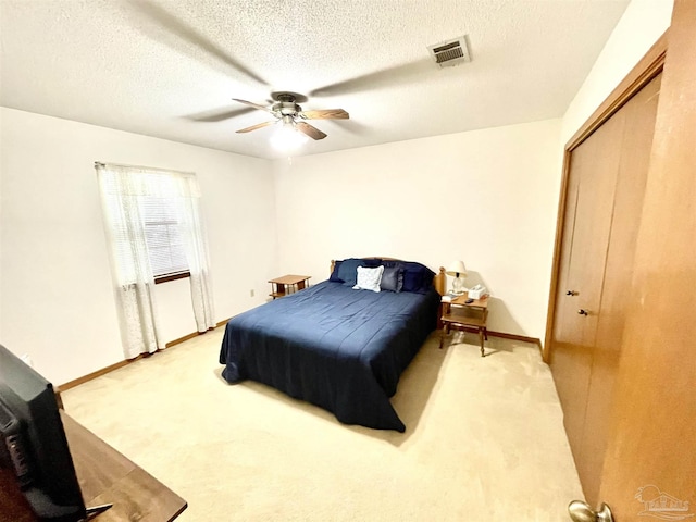 carpeted bedroom with a textured ceiling, a closet, and ceiling fan