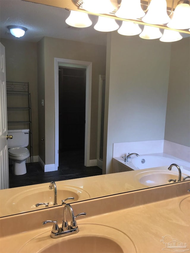 full bath with an inviting chandelier, toilet, a garden tub, and a sink