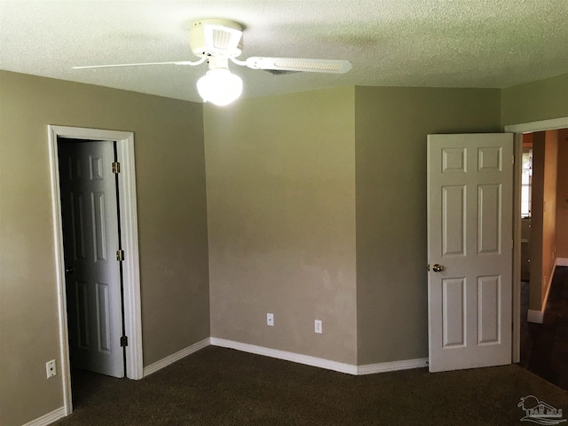 unfurnished bedroom with ceiling fan, a textured ceiling, baseboards, and dark colored carpet