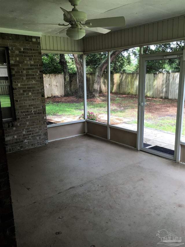 unfurnished sunroom featuring a ceiling fan and a healthy amount of sunlight