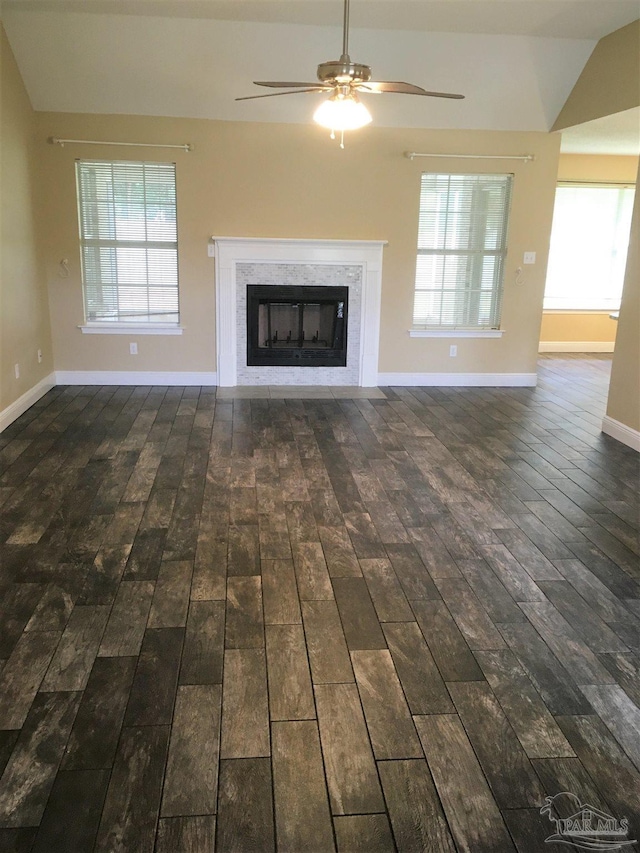 unfurnished living room featuring a ceiling fan, lofted ceiling, wood finished floors, and a high end fireplace