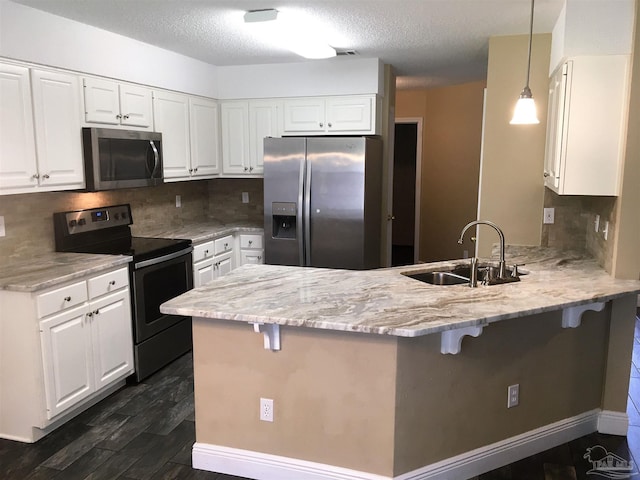 kitchen featuring a sink, stainless steel appliances, a peninsula, a breakfast bar area, and white cabinets