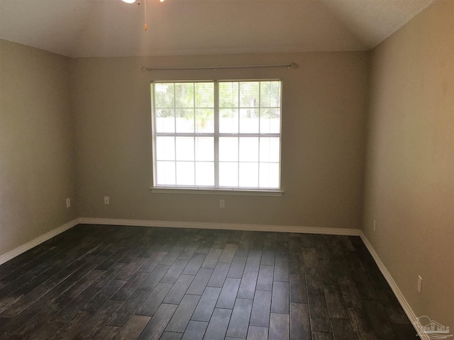 spare room featuring lofted ceiling, baseboards, and dark wood-style flooring