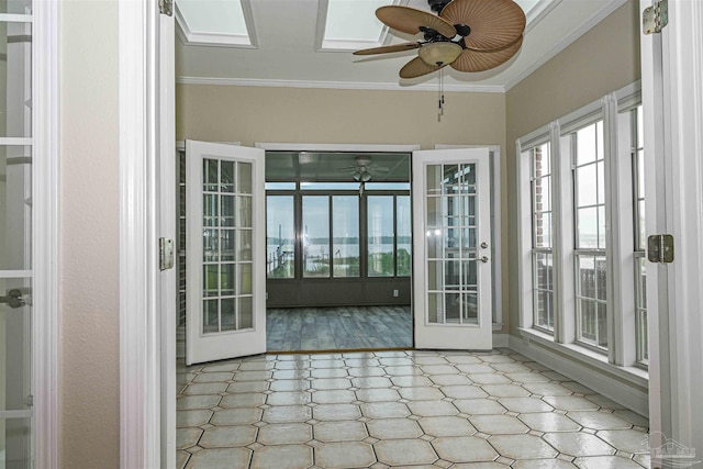 unfurnished sunroom with ceiling fan, a skylight, and french doors