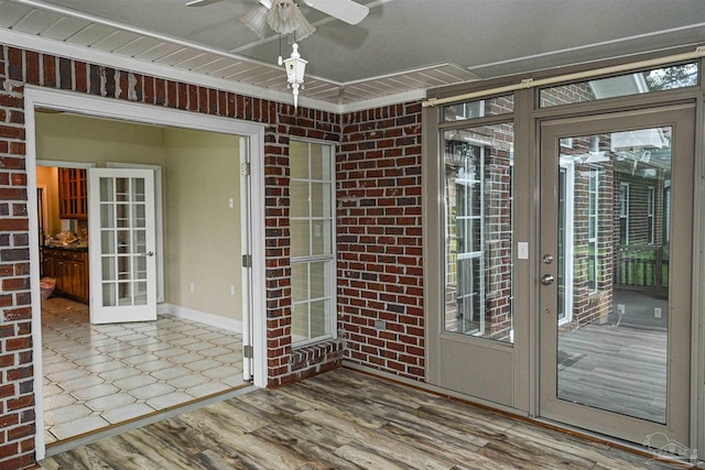 doorway with french doors, ceiling fan, brick wall, and hardwood / wood-style floors