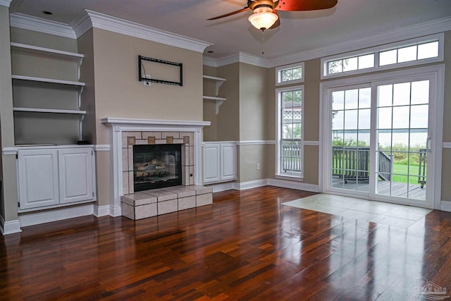 unfurnished living room featuring ceiling fan, ornamental molding, dark wood-type flooring, and built in shelves