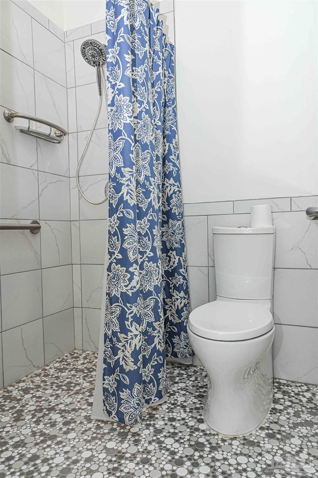 bathroom with tile walls, walk in shower, and toilet