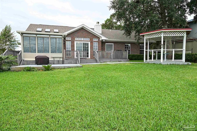 back of house with a deck, a sunroom, and a lawn