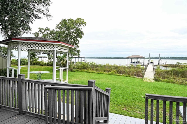 wooden terrace featuring a gazebo, a boat dock, a water view, and a yard