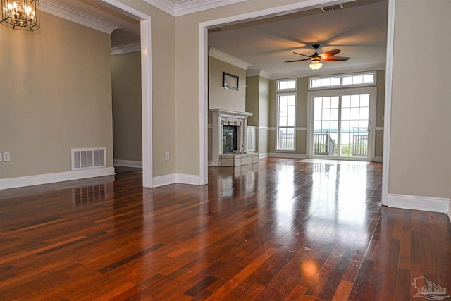 unfurnished living room with dark hardwood / wood-style floors, ceiling fan with notable chandelier, crown molding, and a tiled fireplace