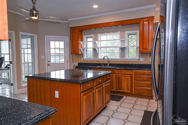 kitchen with a healthy amount of sunlight, stainless steel fridge, a kitchen island, and sink