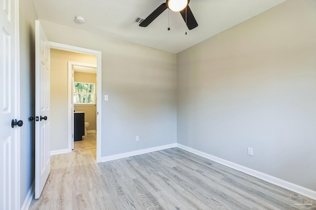 spare room with light wood finished floors, a ceiling fan, a smoke detector, and baseboards