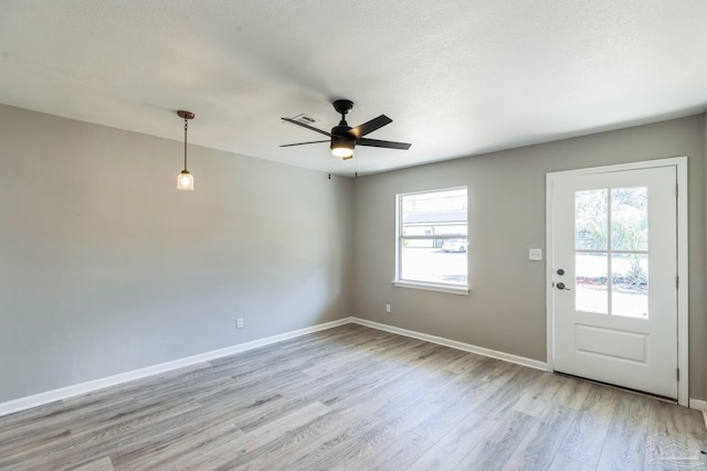 spare room featuring light wood-type flooring, a ceiling fan, and baseboards
