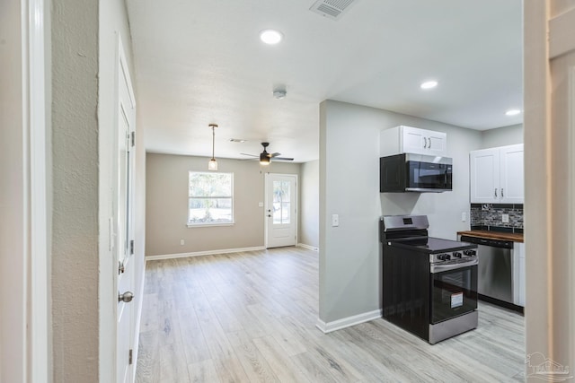 kitchen featuring appliances with stainless steel finishes, white cabinetry, light wood-style floors, baseboards, and backsplash
