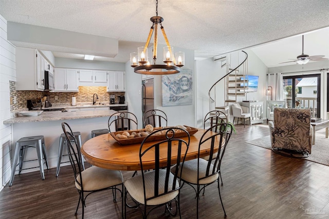 dining room with ceiling fan with notable chandelier, a textured ceiling, stairway, lofted ceiling, and dark wood-style flooring