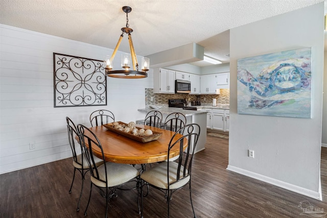 dining area featuring dark wood finished floors, a notable chandelier, a textured ceiling, and baseboards