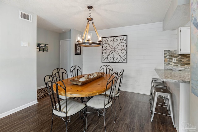 dining space featuring a notable chandelier, baseboards, visible vents, and dark wood-style flooring