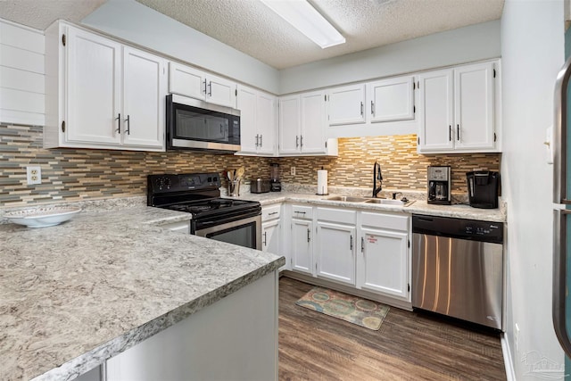 kitchen featuring dark wood finished floors, light countertops, stainless steel appliances, white cabinetry, and a sink