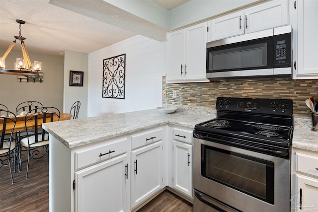 kitchen with stainless steel appliances, tasteful backsplash, a peninsula, and white cabinetry