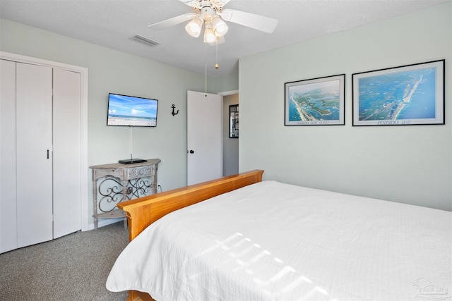 carpeted bedroom with a closet, visible vents, a textured ceiling, and ceiling fan