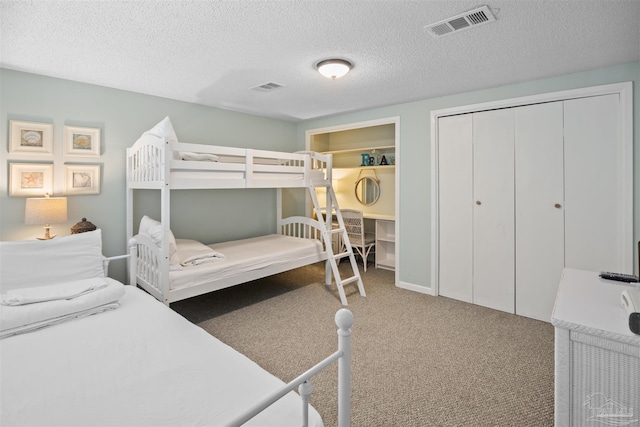 bedroom with a closet, visible vents, a textured ceiling, and carpet floors