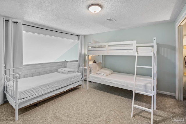 carpeted bedroom featuring visible vents and a textured ceiling