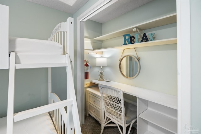 bedroom with a textured ceiling and built in desk