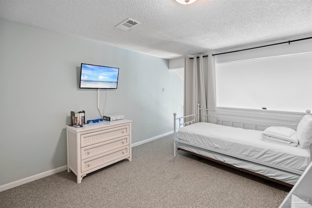 bedroom with visible vents, baseboards, light colored carpet, and a textured ceiling