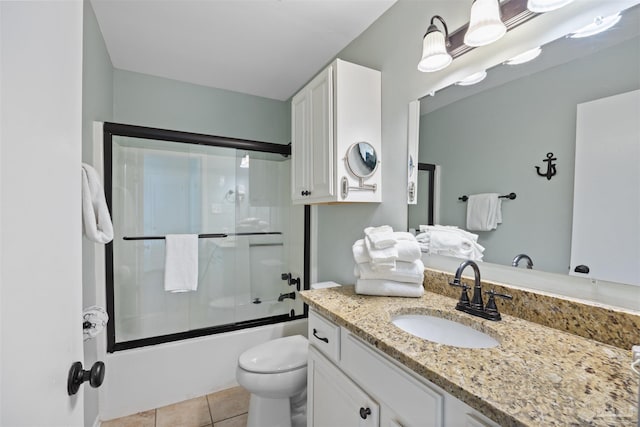 full bath featuring tile patterned flooring, toilet, vanity, and bath / shower combo with glass door