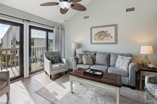 living area featuring light wood finished floors, visible vents, ceiling fan, and vaulted ceiling