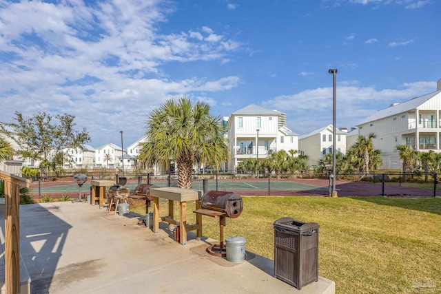 view of home's community featuring a tennis court, a yard, fence, and a residential view