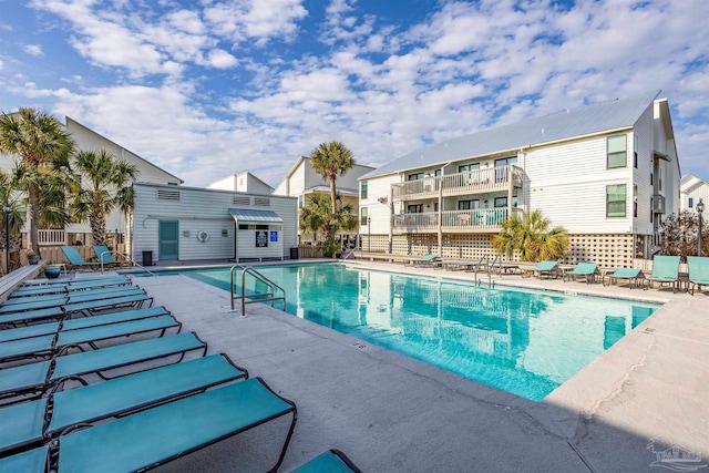 community pool with a residential view, fence, and a patio area