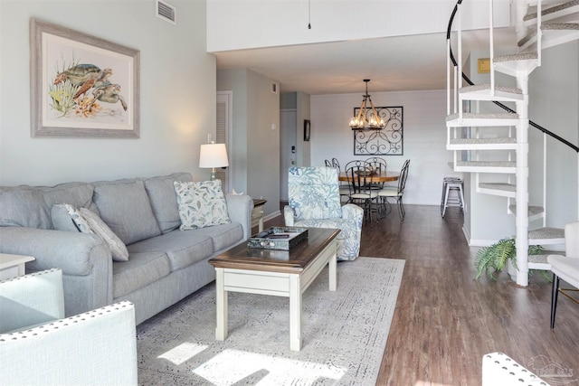 living room featuring visible vents, baseboards, a chandelier, stairs, and wood finished floors