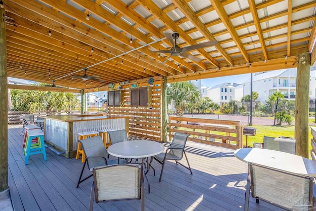 wooden deck with outdoor dining space, ceiling fan, and fence