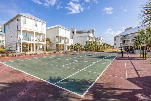 view of tennis court with fence and a residential view