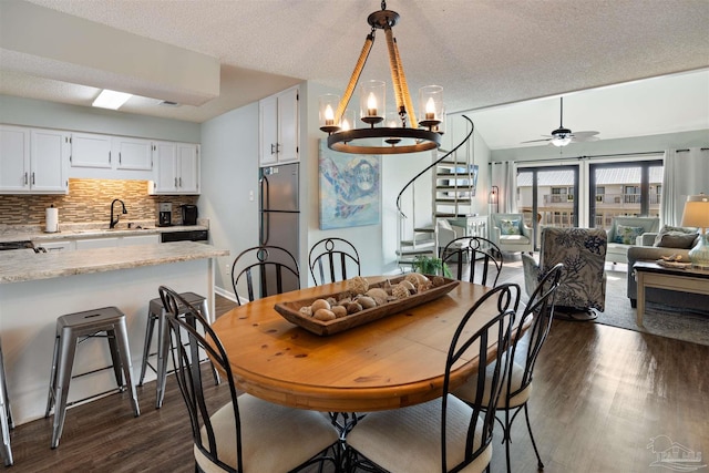 dining room featuring dark wood-type flooring, stairway, lofted ceiling, ceiling fan with notable chandelier, and a textured ceiling