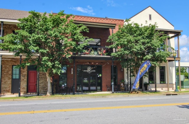 view of front facade with brick siding and a balcony