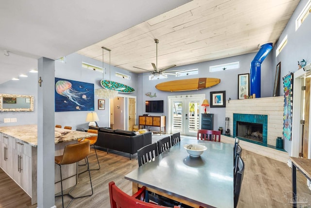 1112 Maldonado Dr, Pensacola Beach, FL 32561 - dining room featuring french doors, a brick fireplace, ceiling fan, light wood-type flooring, and a towering ceiling