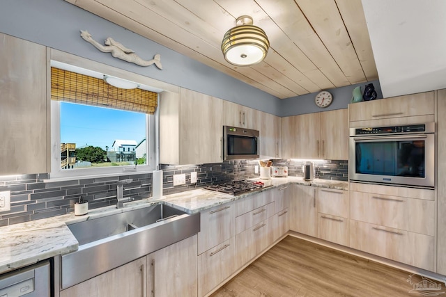 kitchen with light brown cabinetry, light wood-type flooring, light stone counters, stainless steel appliances, and wooden ceiling