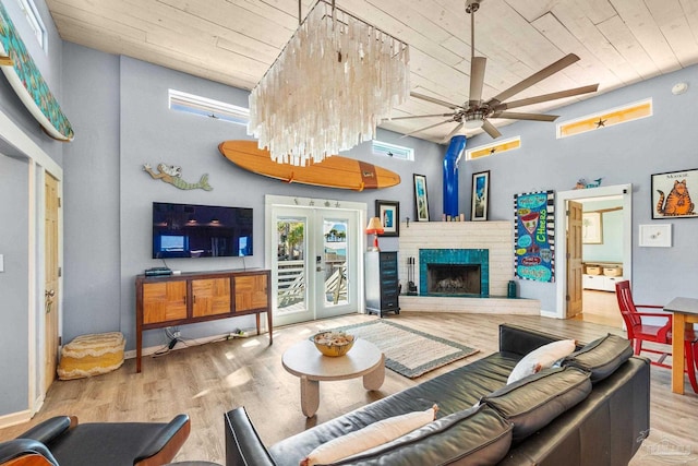 living room featuring french doors, light wood-type flooring, a towering ceiling, wooden ceiling, and a fireplace