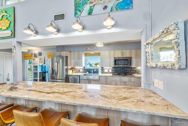 1112 Maldonado Dr, Pensacola Beach, FL 32561 - kitchen featuring appliances with stainless steel finishes, tasteful backsplash, a breakfast bar, sink, and light brown cabinets