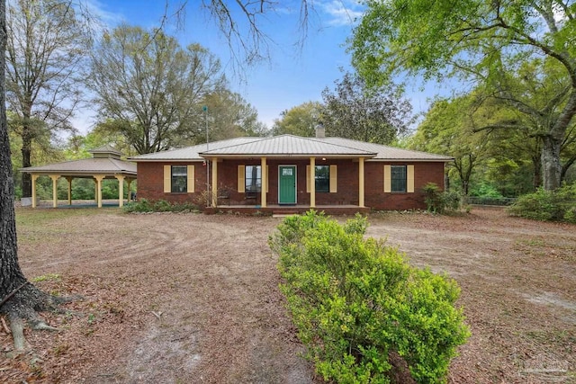 view of front of home featuring driveway, covered porch, metal roof, and a gazebo